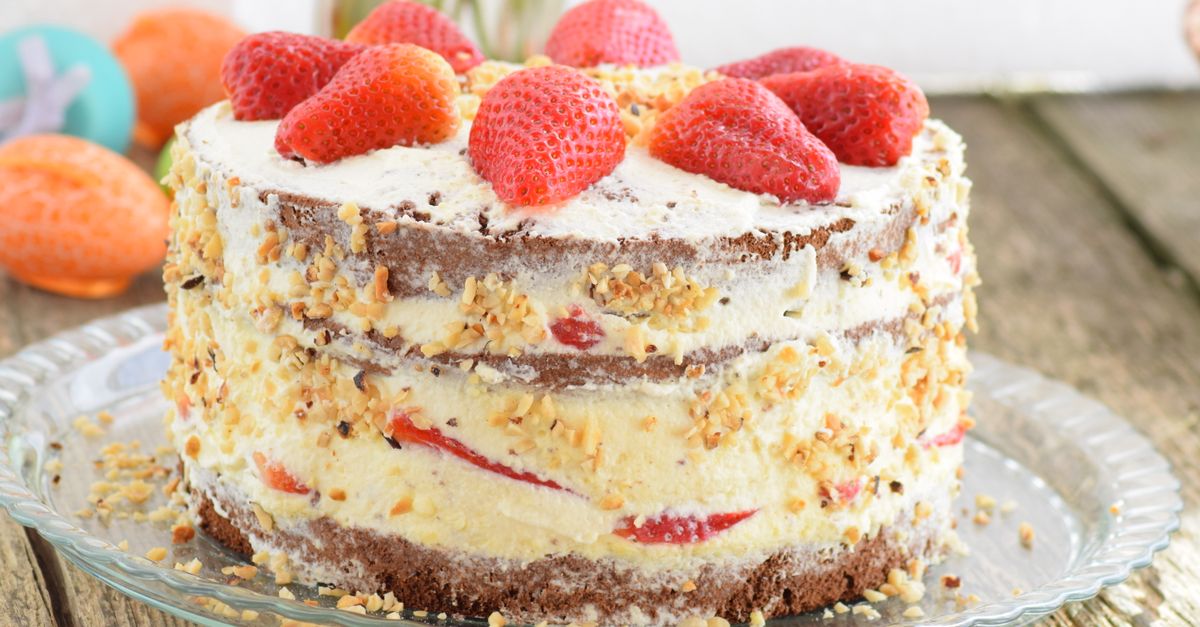 Delicious strawberry-layered cake with cream and nuts on a rustic wooden table. Perfect for dessert enthusiasts.